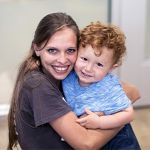 teacher and two year old boy hugging at daycare