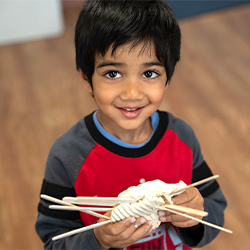 little boy smiling and holding craft